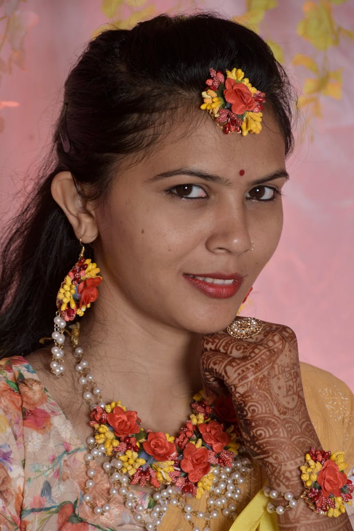 South Asian bride showcasing intricate mehndi and vibrant floral jewelry in a traditional outfit.