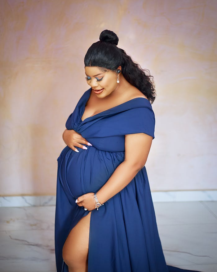 Beautiful pregnant woman in elegant blue gown, indoors.