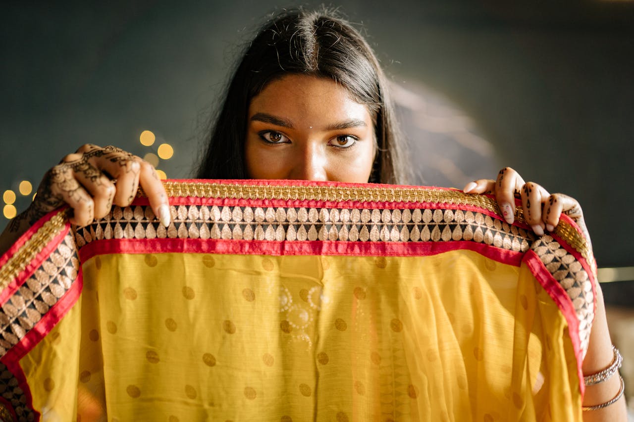 Close-up of a South Asian woman with mehndi, holding a vibrant yellow dupatta.